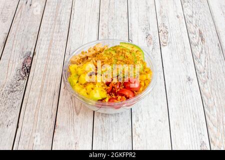 Gesunde Hähnchenschüssel mit Mango-Tacos, in Scheiben geschnittener Avocado, knuspriger Zwiebel, weißem Reis, süßem Mais und Kirschtomaten auf einer transparenten Schüssel für Heim d Stockfoto