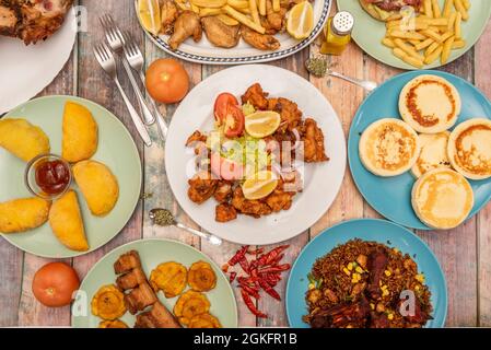 Set von verschiedenen Gerichten der typischen kolumbianischen Küche in schönen blauen und grünen Platten auf Holzhintergrund Stockfoto