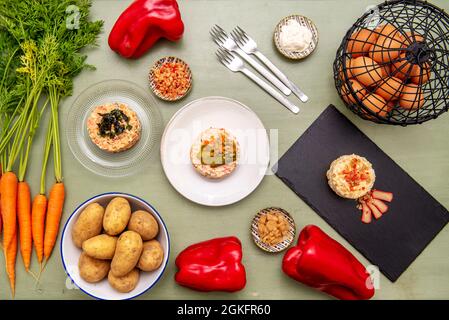 Set aus verschiedenen russischen Salatgerichten auf grünem Holztisch und rohen Zutaten Stockfoto