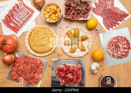 Eine Auswahl an typisch spanischen Gerichten für die Tapas-Bar und beliebte Aufschnitte. Patatas Bravas, Tortilla-Kartoffeln, Kabeljau-Kroketten, Wurstlende, Eichelschinken Stockfoto