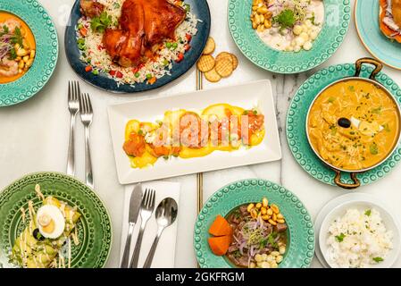 Set aus typisch peruanischen Ceviches, mariniertem Lachs und anderen Fusion-Gerichten, serviert in schönem blauen Geschirr auf einem weißen Marmortisch Stockfoto