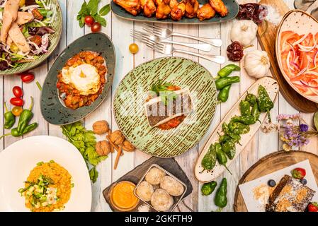 Set von typisch spanischen Gerichten Draufsicht mit Nüssen, Knoblauch, Koriander, Kirschtomaten, zerknittert Kartoffeln, Bauch und Gabeln Stockfoto