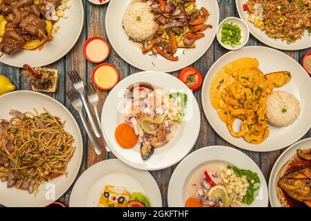 Gerichte der typischen peruanischen Restaurant Essen. Ceviches, Lomo Saltado, Saltado-Nudeln, gebratenes Huhn, Antikuchos, Chaufa-Reis Stockfoto