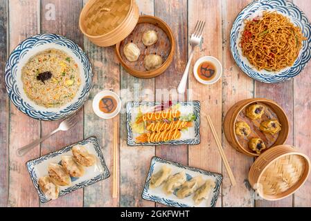 Asiatische und chinesische beliebte Gerichte. Garnelen in Tempura, abwechslungsreiche Dim Sum, gegrillte und gedünstete Gyozas, gebratene Nudeln, drei Köstlichkeiten Reis, Sojasauce. Stockfoto