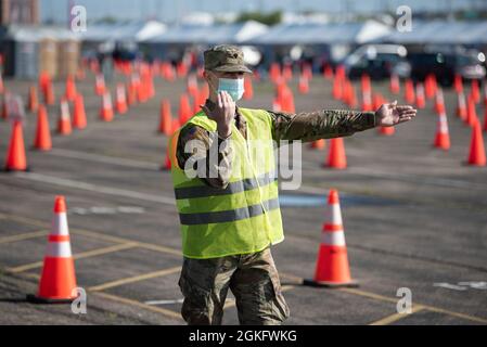 SPC der US-Armee. Logan Kilmon von der Nationalgarde der Kentucky Army leitet den Verkehr in Kentuckys größter Durchfahrungs-Impfklinik COVID-19 im Cardinal Stadium in Louisville, Ky., 12. April 2021. Mehr als 30 Soldaten und Luftwaffe der Kentucky Army und der Air National Guard unterstützen die Klinik, die bis zu 4,000 Patienten pro Tag impfen kann. Stockfoto