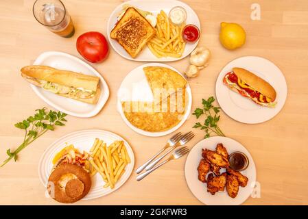 Fastfood-Gerichte in einer Tapas-Taverne. Alitas de pollo bbq, Perrito caliente, Sandwich Mixto, Bocadillo de pollo, Hamburguesa clasica, Tortilla de patata Stockfoto