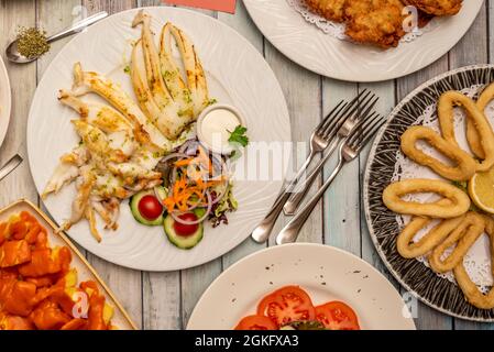 Typische Tapas-Gerichte im Restaurant, gegrillter Tintenfisch, römischer Tintenfisch, Rührei mit Schinken, Kabeljau-Kroketten, Patatas Bravas. Stockfoto