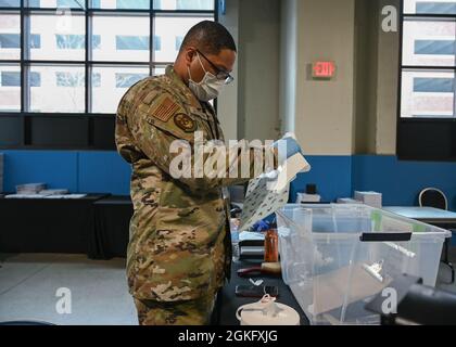 Dante Jefferson, Senior Airman der US Air Force, ein gebürtiger und Luft- und Raumfahrtmechaniker in Hampton, Virginia, mit dem 2. Wartungsgeschwader, dem 2. Bombenflügel, der auf dem Luftwaffenstützpunkt Barksdale, Louisiana, stationiert ist, desinfiziert Clipboards für Gemeindemitglieder im staatlich geführten, staatlich unterstützten Ford Field COVID-19 Community Vaccation Center in Detroit, April 12, 2021. Jefferson ist Teil einer Gruppe von Luftmännern, die der 64th Air Expeditionary Group, der 1. Abteilung, zugeordnet sind und die bei den Impfbemühungen helfen. Jefferson ist bereit, insbesondere der Gemeinde Detroit eine helfende Hand zu geben Stockfoto