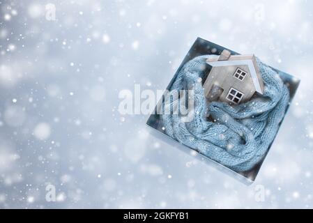 Holzhaus in einem blauen Strickschal in der Box eingewickelt. Stockfoto