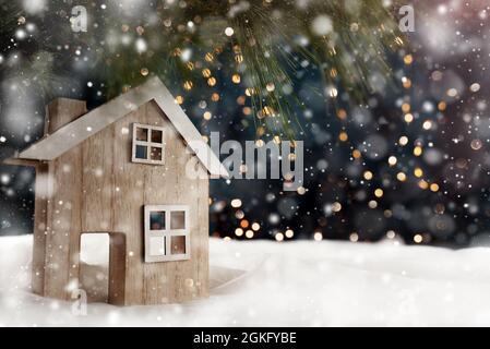 Ein Holzhaus auf der Fensterbank bei Schneefall Stockfoto