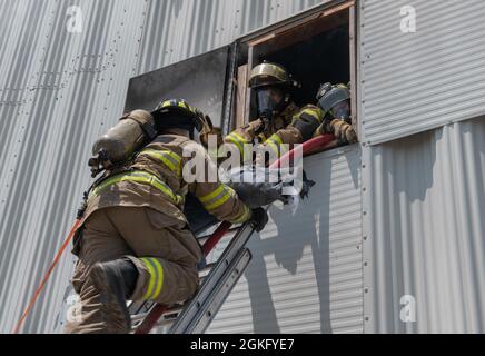 Mitglieder des Joint Base San Antonio 902nd Civil Engineer Squadron Fire Emergency Service und Feuerwehrleute der Feuerwehr Schertz und Cibolo retten während einer Feuerübung am 14. April 2021 in der Joint Base San Antonio-Randolph, Texas, ein Übungspuppe aus einem Gebäude durch ein Fenster. Die Schulung ermöglichte Konsistenz in den Techniken der JBSA-Feuerwehrleute und der Mitglieder der Feuerwehr beider Gemeinden. Stockfoto