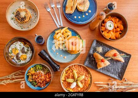 Set aus schönen Keramikplatten mit zerbrochenen Eiern mit Trüffelsauce, Nachos mit Guacamole, Patatas Bravas, hawaiianischer Lachsschüssel, Edamame. Snacks Stockfoto