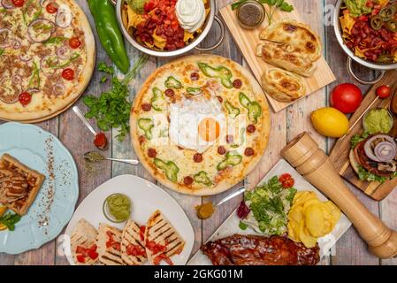 Set von Gerichten aus verschiedenen Kulturen Grillrippchen, mexikanische Quesadillas, Hamburger, Pizzas, Nachos mit Guacamole, Argentinische Empanadas, Waffel mit Choc Stockfoto