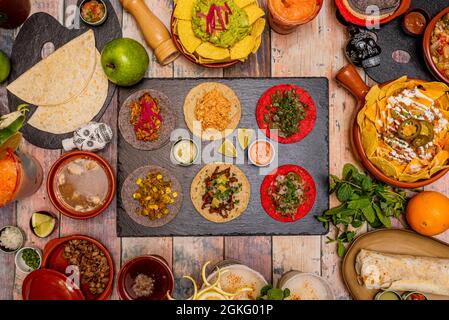 Set von beliebten Gerichten der mexikanischen Kultur. Cochinita tacos, Pastor tacos, Schweinefleisch gezogen, Nopales. Nachos mit Guacamole, komplette Nachos, Burrito, Rindfleisch w Stockfoto