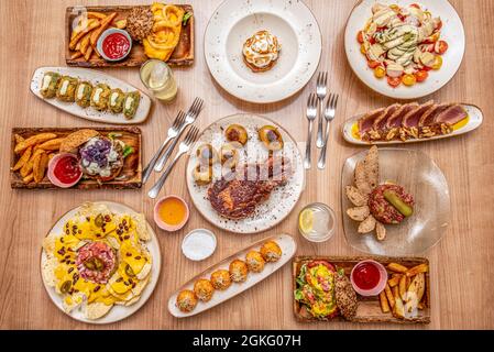 Internationale Gerichte. Gegrillter spanischer Entrecote, amerikanische Hamburger, Nachos mit mexikanischer Guacamole, Rottunfisch-Tartar und Spinat und Schinken-cro Stockfoto