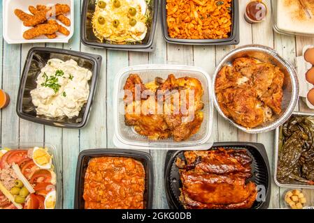 Gerichte der Lebensmittel in einer Hausdienst-Küche zubereitet. Gebratene Hühner, grillrippen, geröstete grüne Paprika, Aioli-Kartoffeln, Krümel, Landsalat. Stockfoto