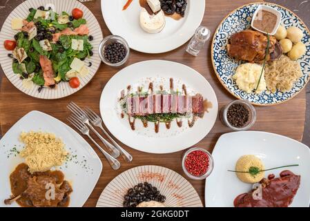 Gerichte der internationalen Gastronomie. Rotes Thunfisch-Tataki, grillrippchen, selbstbewusste Ente, Schweinefleisch mit Sauerkraut, Lachs und Spinatsalat. Stockfoto