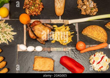 Set von Gerichten und Tapas der spanischen Küche. Russischer Salat mit gekochtem Ei, gebratenes Huhn mit pommes frites, halbem Kartoffelomelett, fester Ohrenklappe, Knoblauch Stockfoto