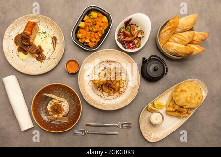 Gerichte der typisch spanischen Gastronomie mit einem schicken Touch. Tintenfisch-Sandwich, Patatas Bravas, Hackbraten, Tomatensalat, russischer Salat mit Crunchies. Stockfoto