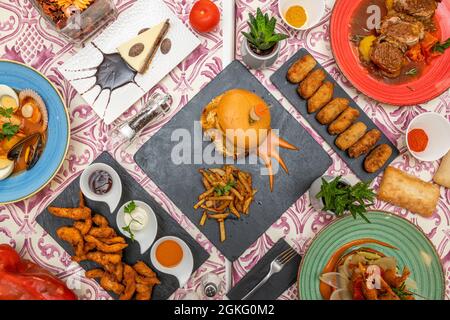 Set von schönen Tellern mit modernen und Techno-emotionalen Speisen. Chicken Fingers, Meeresfrüchte-Suppe, Fisch Burger garniert mit Kartoffeln, Kabeljau Kroketten, Schweinefleisch Stockfoto