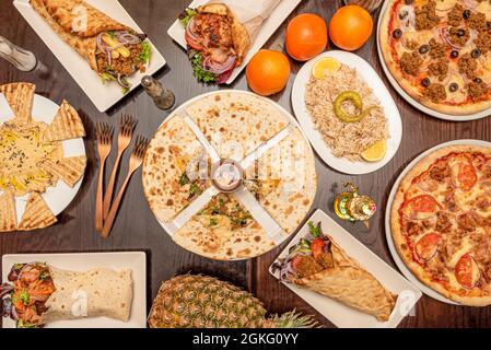 In einem arabischen Fusion-Restaurant zubereitete Gerichte mit Kebab-Quesadillas, Halal-Pizza, Shawarma-Pizza, Dip-Hummus und Basmati-Reis. Stockfoto