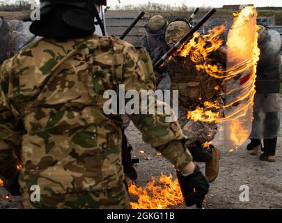 Spc. Aaron Beeber, ein Kavalleriescout mit Truppe B, 1. Squadron, 113. Kavallerieregiment, Iowa Army National Guard, durchläuft am 12. April 2021 beim Training der Feuerphobie im Camp Novo Selo, Kosovo, Flammen. Truppe B ist dem Manöver Bataillon für das Regionalkommando Ost, Kosovo Force, zugeordnet. Ungarische Streitkräfte Truppen trainierten die 1-113. Auf Einzel-, Kader- und Zugebene. Stockfoto