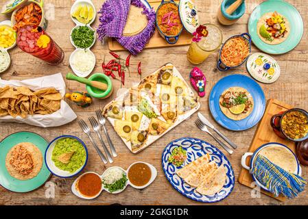 Set von Tellern und Geschirr von beliebten mexikanischen Speisen. Synchronisierte Quesadillas, Tinga-Tacos, Maischips, Cochinita pibil, Tacos al Pastor, Guacamole in Stockfoto