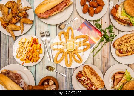 Eine Auswahl an typischen Gerichten, die in spanischen Tavernen serviert werden. Squid a la romana, Patatas Bravas, gebratene Flügel, Speck-Sandwich, hausgemachte Kroketten Stockfoto