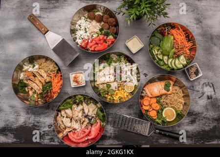 Set aus Metallschüsseln gefüllt mit Poke, Salaten, Quinoa und allen Arten von gesunden Lebensmitteln Stockfoto