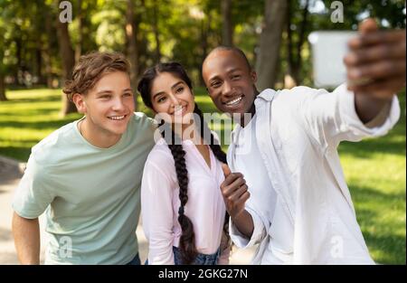 Momente festhalten. Fröhlicher afroamerikanischer Student, der Selfie mit seinen Universitätsfreunden auf dem Campus machte Stockfoto