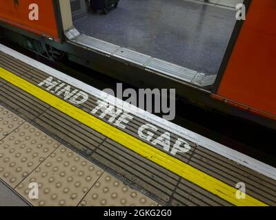 Markierungen und Worte auf einer Plattform warnen die Passagiere vor der Lücke zwischen der Plattform und dem Zug. Stockfoto