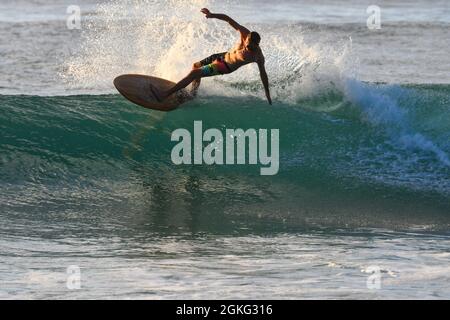 Surfer Surfen Sie bei Sonnenuntergang in den türkisfarbenen karibischen Wellen Stockfoto