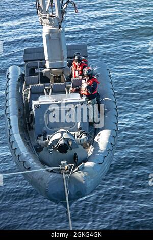 210414-N-OI940-1049 KELTISCHES MEER (14. April 2021) Seeleute, die dem amphibischen Transportdockschiff USS San Antonio (LPD 17) zugewiesen wurden, werden während des normalen Schiffsbetriebs am 14. April 2021 mit einem Rigid-Rumpf-Schlauchboot (RHIB) mit dem Knickboomkran des Schiffes angehoben. San Antonio ist in der Keltischen See mit dem Amphibiengeschwader 4 und der 24. Marine Expeditionary Unit (24. MEU) als Teil der Iwo Jima Amphibious Ready Group tätig. Stockfoto