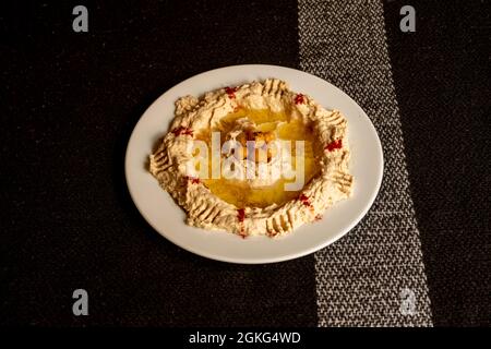 Traditioneller Kichererbsen-Hummus mit in der Mitte gekochten ganzen Kichererbsen, viel Olivenöl und Paprikapulver Stockfoto