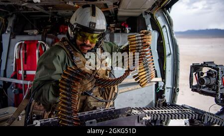 210414-N-PH222-1294 Fallon, Nevada (14. April 2021) Naval Air Crewman (Hubschrauber) 2nd Class Christopher Sahagun aus Ventura, Kalifornien, der „Black Knights“ of Helicopter Sea Combat (HSC) Squadron 4 zugewiesen wurde, bereitet in einem MH-60S Knighthawk-Hubschrauber während einer Live-Feuerübung in der Nähe der Naval Air Station (NAS) Fallon im Kaliber .50 für ein GAU-21 Maschinengewehr vor. Ein GAU-21 erzeugt 1,100 Schuss pro Minute zyklische Brandrate unter Verwendung eines offenen Bolzenbetriebs und eines doppelten Rückstoßpuffers. Air Wing Fallon ist Teil des Trainingszyklus für die Trägerluftflügel der Marine vor dem Einsatz. HSC Stockfoto