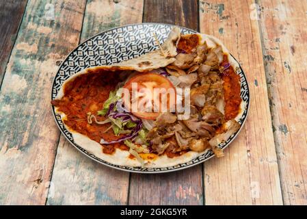 Lahmacun, zubereitet vom arabischen Koch mit Lammkebab-Fleisch, Tomatenscheibe, weißer Zwiebel, purpurem Grünkohl auf einem schönen Teller Stockfoto