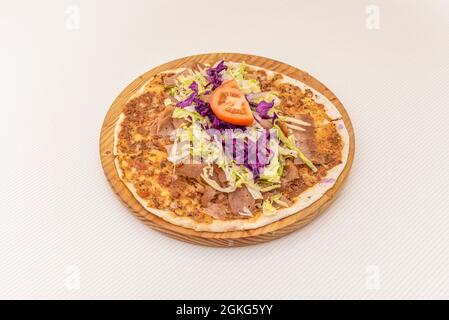 Arabische Kebab-Pizza, Lahmacun mit purpurfarbenem Kohl, Tomate, geriebener Eisbergsalat auf Holzplatte. Stockfoto