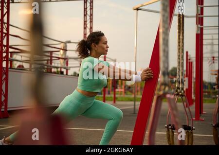 Sportliche reife afroamerikanische Athletin wärmt sich auf und dehnt ihren Körper vor und nach dem Training am frühen Morgen. Sportlerin arbeitet Stockfoto