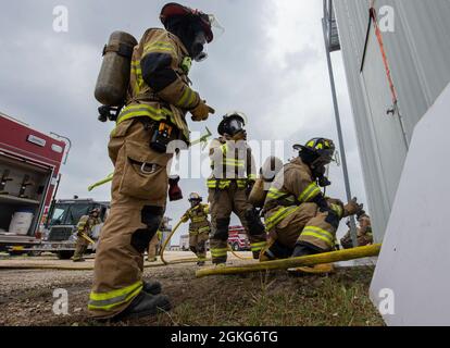 Feuerwehrleute der Cibolo Fire Department legen ihre Ausrüstung an, bevor sie an einer Live-Feuerübung am 14. April 2021 in der Joint Base San Antonio-Randolph, Texas, teilnehmen. Schertz Fire Rescue leitete die Schulung, die sich auf die Rettungstaktik Vent Enter Search konzentrierte, bei der ein Feuerwehrmann von einem Außenbereich einer Struktur aus Zugang erhält, um eine gezielte Suche nach Opfern durchzuführen. Stockfoto