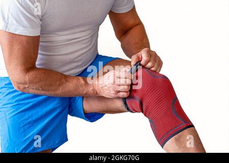 Der Mann stellt eine Kompressionsbandage am Kniegelenk ein. Sportverletzung Stockfoto
