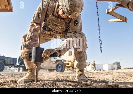 US Army Sgt. Kevin Jaimes aus Austin, Texas, ein Soldat der Task Force Spartan Division Tactical- Jordan, zerstoßt während einer Validierungsübung zur Verlegung des taktischen Einsatzzentrums, bekannt als „Jumping the TAC“, den Erdleiter eines Generators in den Boden. Er wurde am 14. April 2021 eingesetzt. Dies war das erste Mal, dass Soldaten der 36. Infanterie-Division diese Art von Manöver im Einsatz durchführten. Die Soldaten platzierten mehr als eine Meile Konzerthalle, um die physische Sicherheit des Standorts zu gewährleisten, und eine kleine Gruppe von Signalsoldaten sorgte dafür, dass das Computernetzwerk sofort einsatzbereit war und die bereitstellen konnte Stockfoto