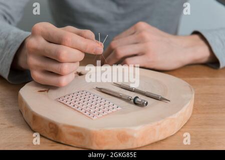 Akupunkturbehandlung an den Händen des Mannes. Rehabilitation mit alternativer Medizin. Akupressurinstrumente auf Holzhintergrund. Stockfoto