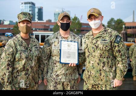 Boston (15. April 2021) Master-at-Arms 1. Klasse Travis Hargerty, Mitte, aus Gilbert, Arizona, wird vom Kommandanten der USS Constitution Cmdr zum Senior Sailor of the Quarter der Verfassung ernannt. John Benda, rechts, und der Vizedirektor, Navy Staff Rear ADM. Jacquelyn McClelland. USS Constitution, das älteste in Auftrag gegebene Kriegsschiff der Welt, spielte eine entscheidende Rolle in den Barbarenkriegen und dem Krieg von 1812 und verteidigte von 1797 bis 1855 aktiv die Seewege. Während des normalen Betriebs bieten die an Bord der USS Constitution stationierten Aktivsegler kostenlose Touren an und bieten öffentliche Besichtigungen an Stockfoto