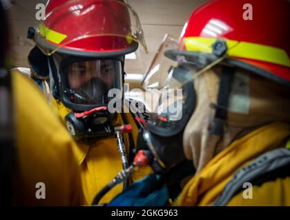 210415-N-DA693-1084 PAZIFISCHER OZEAN (APR. 15, 2021) Seeleute, die an Bord des Militärkrankenhauses des Sealift Command, USNS Mercy (T-AH 19), der eingeschifften medizinischen Behandlungseinrichtung, zugewiesen wurden, führen während einer Übung am 15. April einen Buddy-Check eines Feuerwehrensembles an einem Damage Control Schließfach durch. Mercy ist auf dem Weg vor der Küste Südkaliforniens, um die dynamischen Grenzflächentests durchzuführen, bei denen die Luftfahrteinrichtungen des Schiffes auf Kompatibilität mit der V-22 Osprey und MH-60 Seahawk überprüft und bei widrigen Wetterbedingungen Start- und Wiederherstellungsfenster festgelegt werden. Mercy kehrte kürzlich in seinen Heimathafen in San D zurück Stockfoto