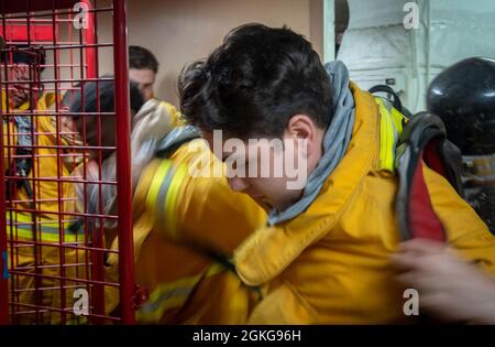 210415-N-DA693-1046 PAZIFISCHER OZEAN (APR. 15, 2021) Yeoman Seaman Apprentice Angel Plascencia, eine Verwaltungsangestellte, die an Bord des Militärkrankenhauses des Sealift Command USNS Mercy (T-AH 19) der eingeschifften medizinischen Behandlungseinrichtung zugewiesen wurde, setzt während einer Übung am 15. April ein Feuerwehrensemble an einem Damage Control Schließfach an. Mercy ist auf dem Weg vor der Küste Südkaliforniens, um die dynamischen Grenzflächentests durchzuführen, bei denen die Luftfahrteinrichtungen des Schiffes auf Kompatibilität mit der V-22 Osprey und MH-60 Seahawk überprüft und bei widrigen Wetterbedingungen Start- und Wiederherstellungsfenster festgelegt werden. Mer Stockfoto