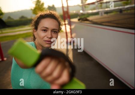 Attraktive Sportlerin trainiert am frühen Morgen, macht ein Ausdauertraining mit Hanteln für Boxen auf dem Sportplatz Stockfoto