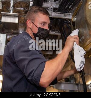 PAZIFIK (15. April 2021) der Engineman Kyle Wilkins aus Ocean City, MD., poliert Messing an Bord des Litoral Combat Ships USS Charleston (LCS 18), April 15. Charleston ist derzeit in der 3. US-Flotte tätig. Stockfoto