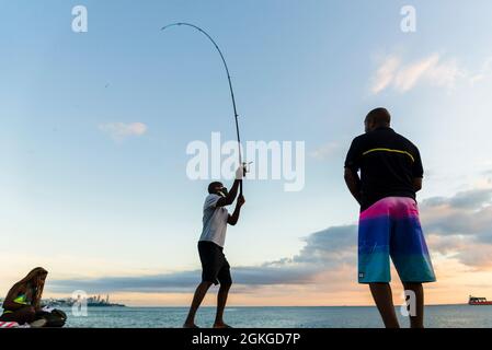 Salvador, Bahia, Brasilien - 23. Mai 2021: Silhouette der Fischer mit ihren Polen bei Sonnenuntergang. Stockfoto