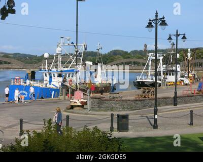 Landschaftsansicht von Booten und Trawlern, die an der Hafenmauer im Fischerhafen Kirkcudbright am Fluss Dee in Südwestschottland festgemacht sind. Stockfoto