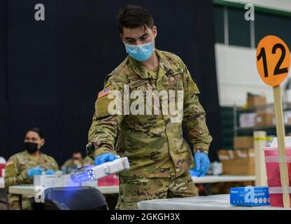 MANGILAO, Guam (16. April 2021) – PFC. Ethan Van Veldhuizen, ein Kampfmediziner, der der 25. Infanteriedivision zugewiesen ist, desinfiziert seine Arbeitsstation, bevor er einen COVID-19-Impfstoff zur Unterstützung des COVID-19-Impfteams des Gesundheitsministeriums von Guam (DPHSS) in einer Impfklinik im Feldhaus der Universität von Guam Calvo verabreicht. Das US-amerikanische Indo-Pacific Command über die US Army Pacific ist weiterhin bestrebt, die Federal Emergency Management Agency im Rahmen der Reaktion der gesamten Regierung auf die COVID- Stockfoto